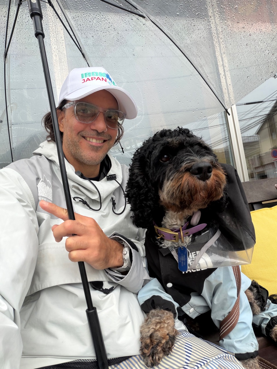 Todd Foxx smiling with his dog Jordan under an umbrella in Tokyo